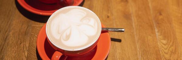 Two red cups of coffee wooden table showcasing intricate latte art. photo
