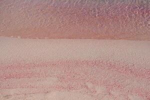 Pink sand and sea wave. Beach with pink sand in Elafonisi, Krit, Greece. Design background wallpaper with copy space. Sand texture pattern photo
