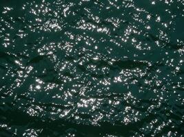 Water surface high contrast topview. Sun glare on water. Background abstracted wallpaper texture photo
