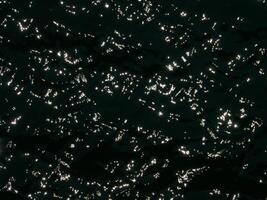 Water surface contrast top view. Sun glare on water black and white edit. Background abstracted wallpaper texture photo