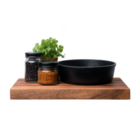 A black cast iron bowl sits on a wooden cutting board, accompanied by jars of spices and fresh cilantro, isolated on a white background, ideal for culinary presentations. png