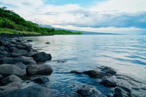 Serene Volcanic Lake Shore with Lush Vegetation and Rocky Shoreline photo