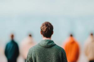 A solitary figure stands with his back to the camera, contemplating amidst a blurred crowd. The image evokes feelings of solitude, photo