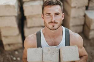 Portrait of a Strong Construction Worker. A muscular man holds bricks, showcasing his physical strength and dedication to his cons photo