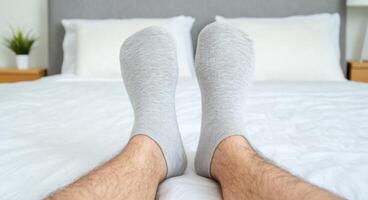 Relaxing in Comfort A Man's Feet in Grey Socks on a Cozy Bed. A Peaceful and Serene Image Representing Relaxation and Rest at Home photo