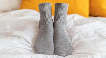 Cozy Grey Socks on a White Bed A Symbol of Relaxation and Comfort at Home. Soft Fabric, Warm Texture, and a Peaceful Atmosphere. P photo