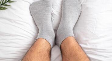 Relaxing at Home A of Legs in Cozy Grey Socks on a White Bed. A Simple, Minimalist Lifestyle Image Evoking Feelings of Peace and photo