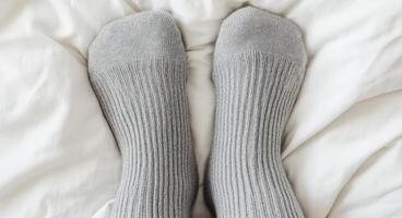 Cozy Grey Socks on a White Bed A Symbol of Relaxation and Comfort at Home. Find peace and tranquility in the simple pleasures of l photo