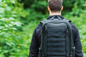 A man with a backpack on his back in a forest, enjoying a journey through nature. A perfect image for travel blogs and adventure a photo