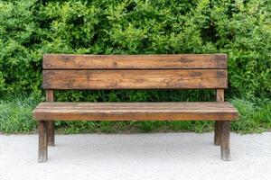 Rustic Wooden Park Bench Against Lush Greenery A Serene Outdoor Sitting Space. Perfect for Relaxation and Enjoying Nature's Beauty photo