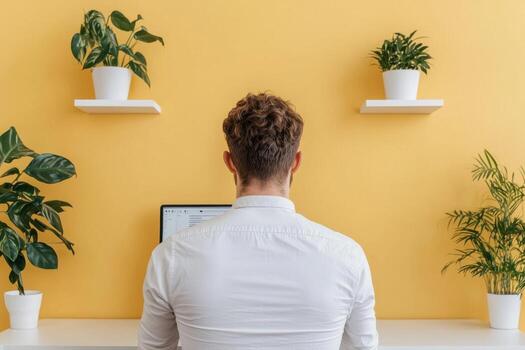 Man Working on Computer at Home Office with Plants. Stylish Minimalist Workspace, Productivity and Focus Concept. Serene and Calm photo