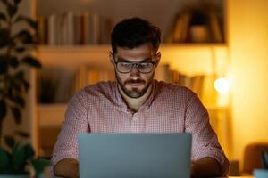 Focused Man Working on Laptop at Night in Cozy Home Office. Concentrated Professional Working Late on Project. Serene and Calm Atm photo