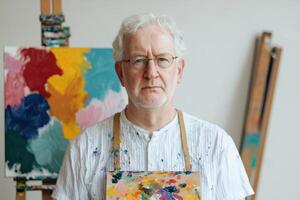 A Portrait of a Mature Male Artist in His Studio, Focused and Immersed in His Creative Process, Surrounded by Colorful Abstract Pa photo
