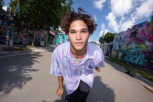 Young Man in Striped Shirt Skates Down a Vibrant Street, Embracing Urban Style and Summer Vibes. A Colorful and Energetic Portrait photo