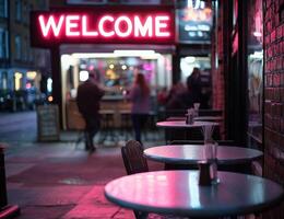 Neon welcome sign shines over cafe tables, street scene background at night photo