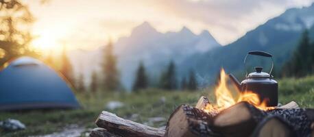 Tent camping with campfire, kettle, and mountains at sunset for travel ads photo