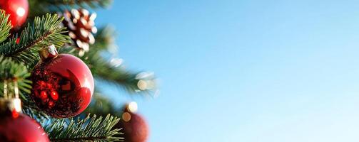 Christmas tree with red ornaments against a clear blue sky photo