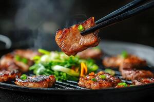 Grilled pork on hot pan, steam rising, chopsticks picking up piece photo
