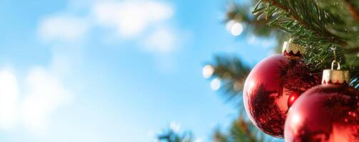 Red ornaments on Christmas tree against blue sky, festive holiday scene photo