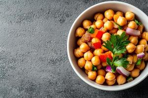 Chickpea salad with herbs and red onion in bowl on dark background photo