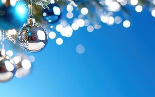 Christmas ornaments on a tree against a blue sky background, ideal for holiday greetings photo