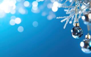 Silver ornaments hanging on frosty branch against blue bokeh background for holiday greeting cards photo