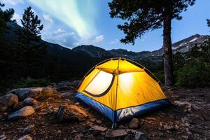 Illuminated tent under aurora borealis in mountain campsite photo