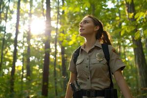 Forest ranger looks up at sunlight through trees during patrol photo