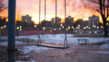 Lonely swing in winter park with city buildings at sunset. Hope concept photo
