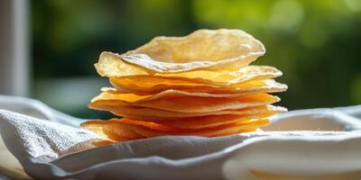Stack of crispy wafers on cloth, blurred foliage background for packaging photo