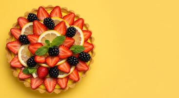 Fruit Tart with Strawberry, Blackberry, and Lemon Slices on Yellow Background photo