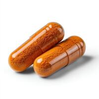 Two capsules of Finely ground dry Turmeric isolated on white background. photo