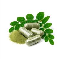 Finely organic dried Moringa powder in capsules isolated on white background photo