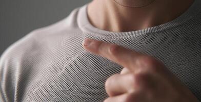 A person demonstrates a textile with water repellent properties. The fabric showcases a unique mesh design, emphasizing both cleanliness and safety in casual clothing. Ideal for active lifestyles. photo
