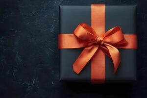 Elegant Gift Box with Orange Ribbon on Dark Background for Celebratory Occasions photo