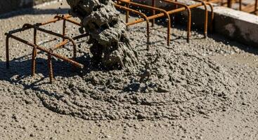 Pouring fresh wet concrete onto a building foundation with visible rebar photo
