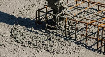 Pouring wet concrete onto a rebar foundation at a construction site photo