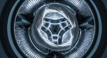 Inside a washing machine drum with white laundry and water during a wash cycle photo