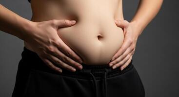 Woman holding her excess belly fat with hands, highlighting weight and body image. photo