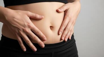 Close up of woman hands gently touching her stomach for health and body care photo