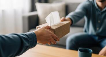 Close up of a hand offering a tissue box, symbolizing comfort and support photo