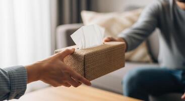 Hand offering a box of tissues, symbolizing support and care during a difficult moment. photo