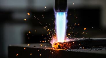 Powerful blue flame from a gas burner intensely heating a piece of raw iron with sparks photo