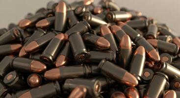 Large pile of pistol ammunition rounds with dark casings and copper tips photo