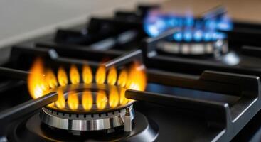 Close up of a gas stove burner with orange and blue flames in a kitchen. photo