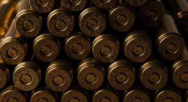 Close up of stacked brass bullet casings showing detailed markings on the base of each cartridge photo