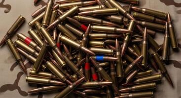 A large pile of rifle ammunition cartridges with brass casings and colored tips photo