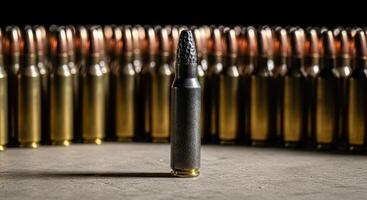A distinct black bullet standing in front of a row of many golden bullets photo
