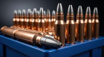 Close up of rifle cartridges with copper casings and dark tips in a blue container photo