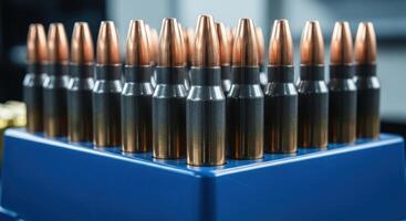 Close up view of rifle bullets with copper tips and dark casings in a blue holder photo
